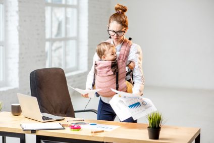 Businesswoman with her baby son working with documents at the office